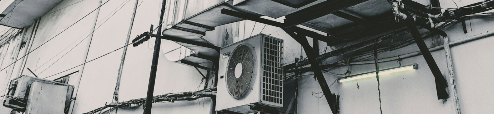 a-black-and-white-photo-of-an-air-conditioner-on-the-side-of-a-building.jpg a black and white photo of an air conditioner on the side of a building